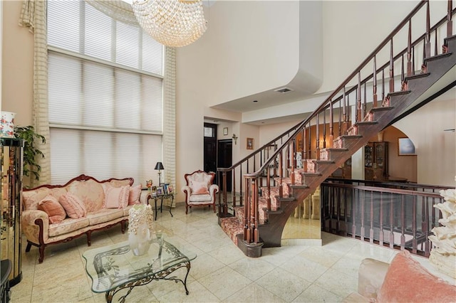 staircase with a notable chandelier, visible vents, tile patterned flooring, and a towering ceiling