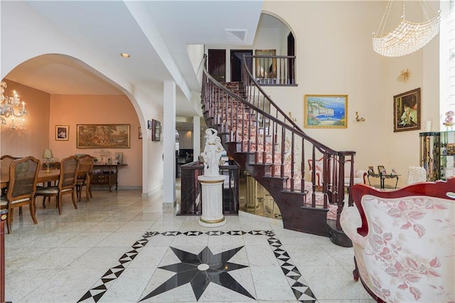 entryway featuring visible vents, stairs, baseboards, a chandelier, and arched walkways