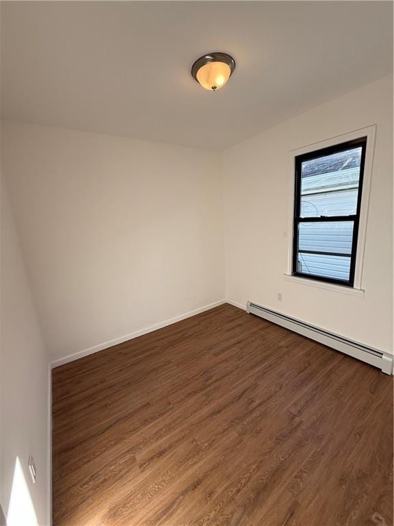 empty room with a baseboard heating unit and dark hardwood / wood-style floors