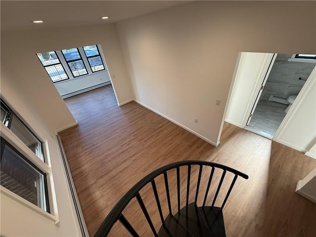 stairs featuring hardwood / wood-style floors and a baseboard heating unit