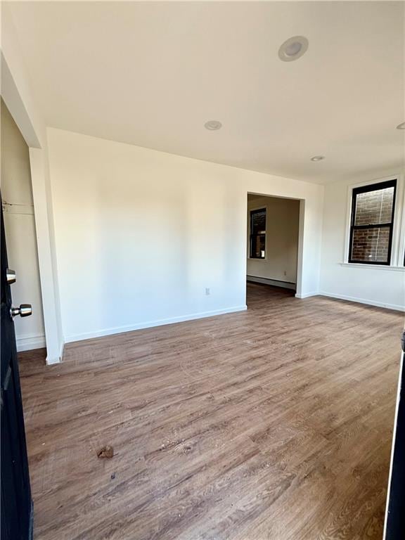 empty room featuring a baseboard radiator and wood-type flooring