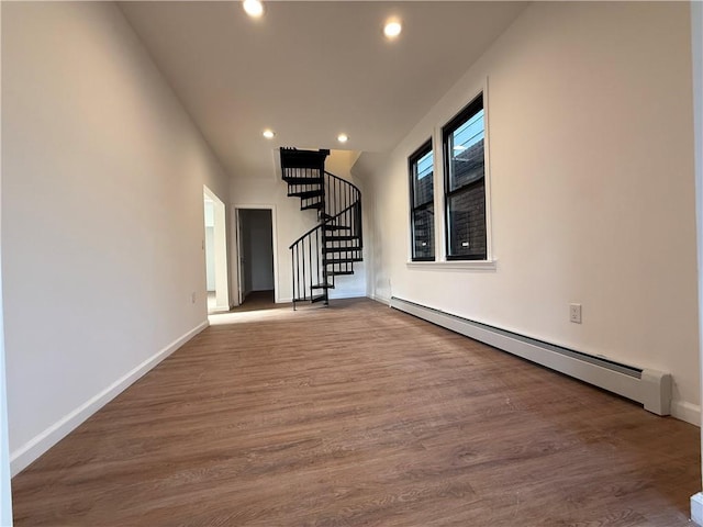 unfurnished living room featuring hardwood / wood-style flooring and a baseboard heating unit