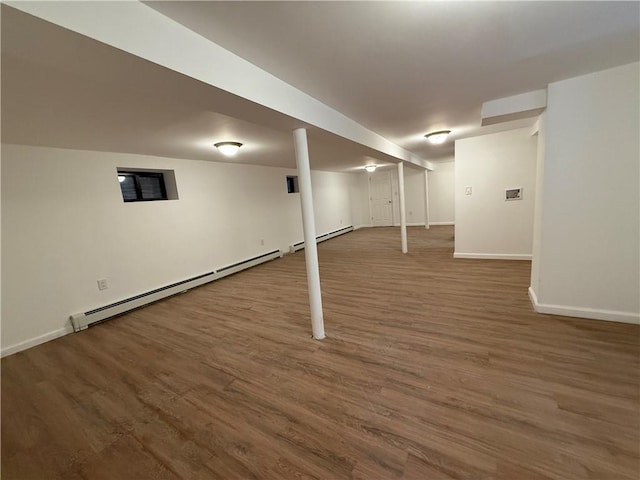 basement with dark hardwood / wood-style floors and a baseboard heating unit