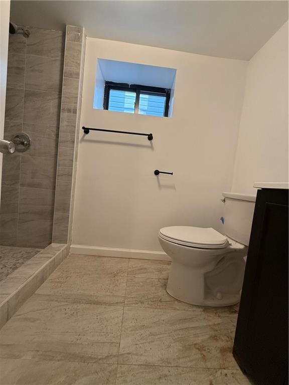 bathroom with a tile shower, vanity, and toilet