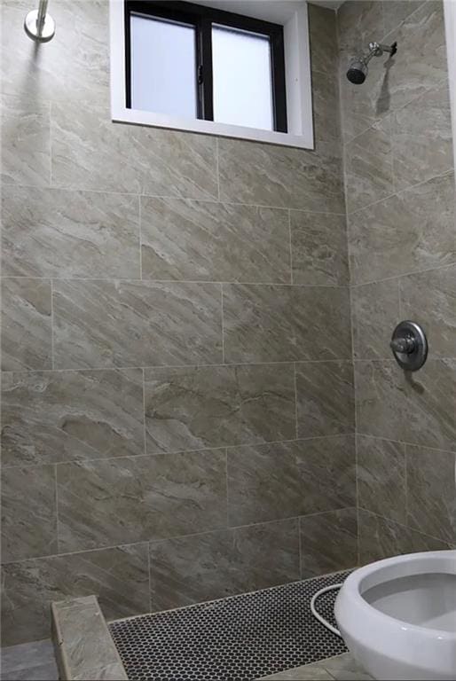 bathroom featuring tiled shower and toilet