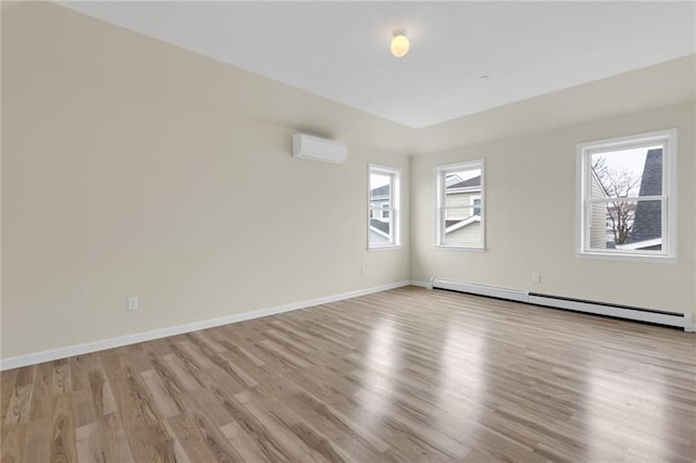 empty room featuring plenty of natural light, a baseboard radiator, a wall mounted AC, and light wood-type flooring