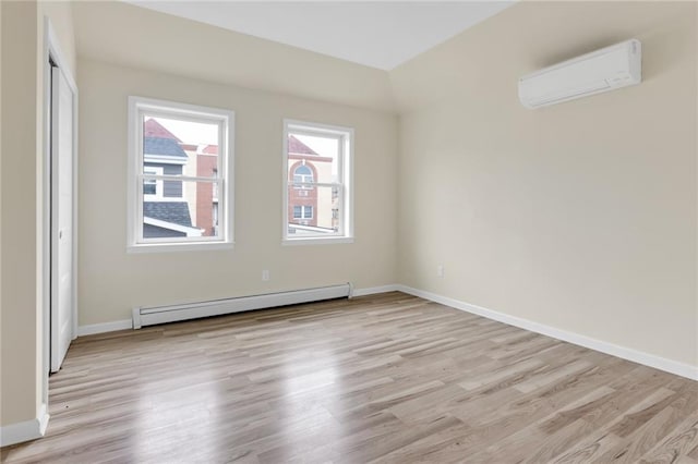 unfurnished room featuring light hardwood / wood-style flooring, a baseboard radiator, and a wall unit AC