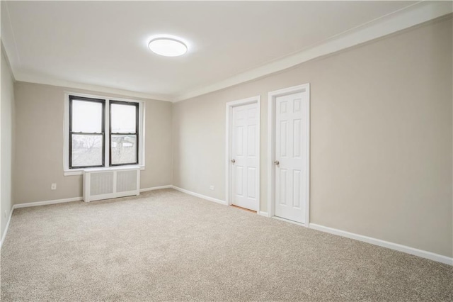 unfurnished room with radiator, light carpet, crown molding, and baseboards