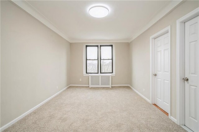 carpeted empty room with radiator and ornamental molding