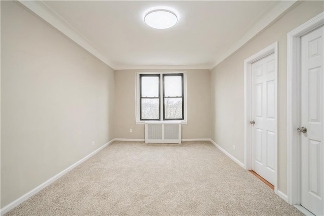 empty room with light colored carpet, radiator, baseboards, and crown molding