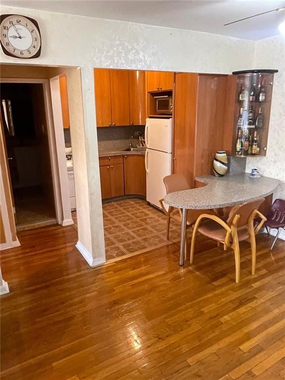 kitchen featuring white refrigerator, dark hardwood / wood-style flooring, and tasteful backsplash