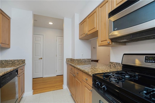 kitchen featuring light tile patterned flooring, appliances with stainless steel finishes, and dark stone countertops