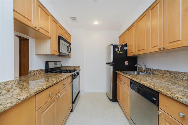 kitchen featuring light brown cabinetry, sink, light stone countertops, and appliances with stainless steel finishes