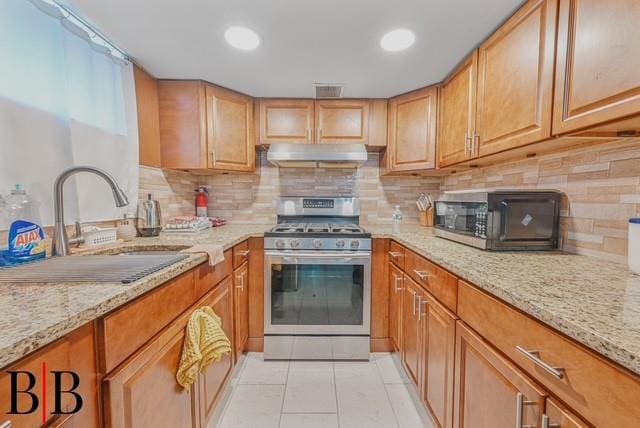 kitchen with light stone counters, sink, light tile patterned floors, and stainless steel appliances