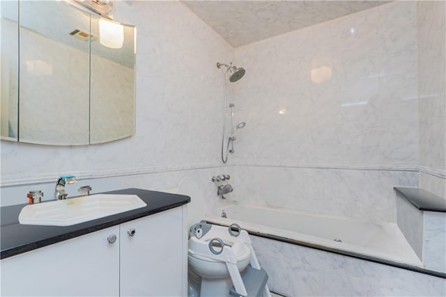 full bathroom featuring tiled shower / bath combo, vanity, and toilet