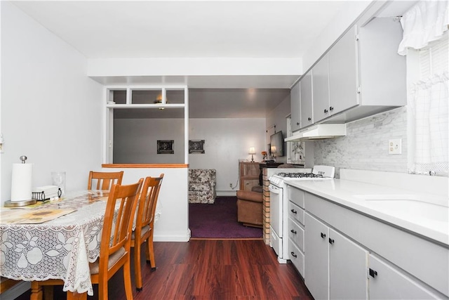 kitchen with sink, backsplash, a baseboard heating unit, gas range gas stove, and dark wood-type flooring