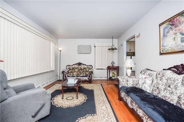 living room with a baseboard heating unit and wood-type flooring