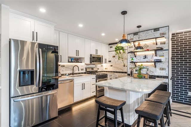 kitchen featuring appliances with stainless steel finishes, pendant lighting, white cabinets, and light stone counters