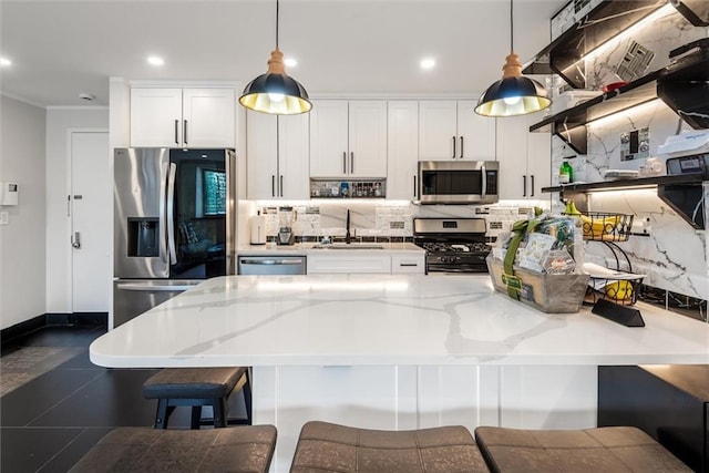 kitchen with stainless steel appliances, sink, pendant lighting, and white cabinets