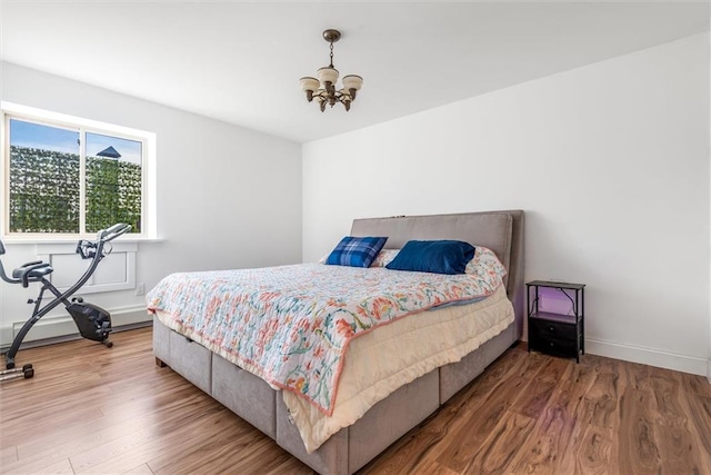 bedroom with hardwood / wood-style floors and a notable chandelier