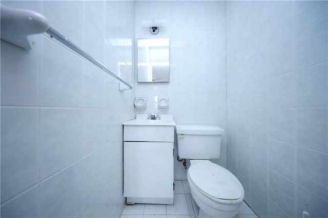 bathroom featuring vanity, toilet, tile patterned flooring, and tile walls