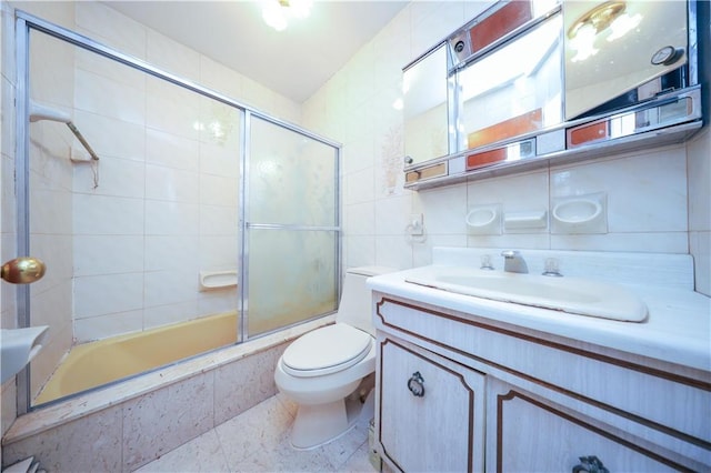 full bathroom featuring bath / shower combo with glass door, tasteful backsplash, tile walls, vanity, and toilet