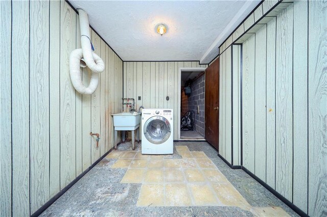 laundry area featuring washer / clothes dryer, wooden walls, and sink