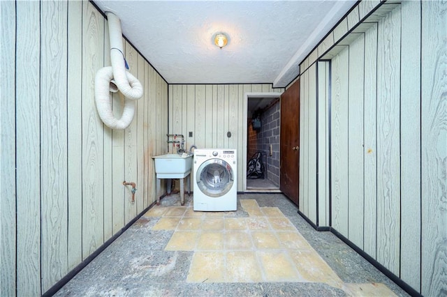 clothes washing area featuring washer / dryer, sink, and wood walls