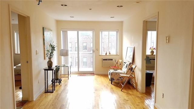 doorway to outside with a wall mounted AC and light hardwood / wood-style floors