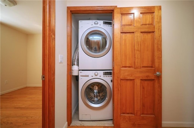 laundry room with stacked washer / drying machine and light hardwood / wood-style flooring