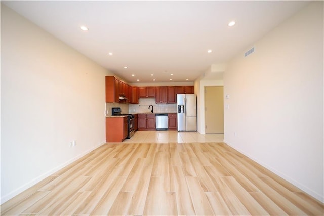 kitchen with sink, stainless steel appliances, light hardwood / wood-style flooring, and backsplash