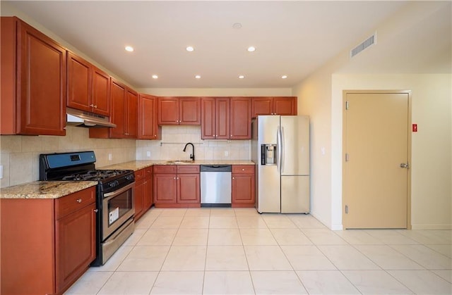 kitchen with light tile patterned floors, sink, backsplash, stainless steel appliances, and light stone counters