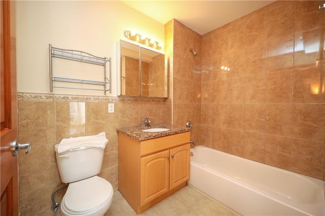 full bathroom with tile patterned floors, tile walls, tiled shower / bath combo, toilet, and vanity