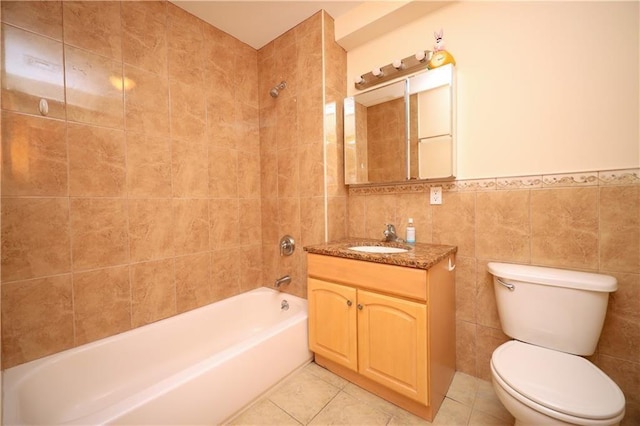 full bathroom featuring tiled shower / bath, tile patterned floors, vanity, tile walls, and toilet