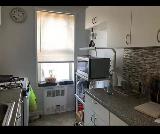 kitchen with white cabinetry, appliances with stainless steel finishes, and radiator heating unit