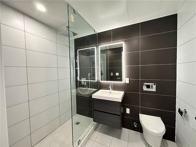 bathroom featuring tile patterned flooring, a tile shower, tile walls, and vanity