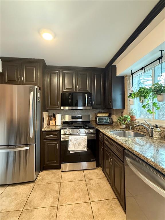 kitchen featuring sink, light stone counters, light tile patterned floors, and stainless steel appliances