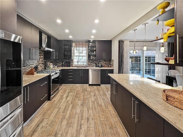 4912 Surf Ave, Brooklyn, NY 11224 - kitchen featuring stainless steel appliances, plenty of natural light, wall chimney range hood, and light wood-type flooring