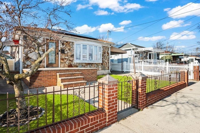 view of front of property with a front lawn, a gate, stone siding, and a fenced front yard