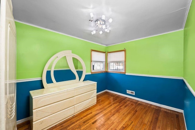 unfurnished bedroom with crown molding and hardwood / wood-style floors