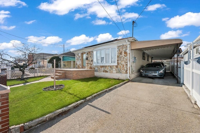 view of front of property featuring stone siding, a front lawn, fence, and aphalt driveway