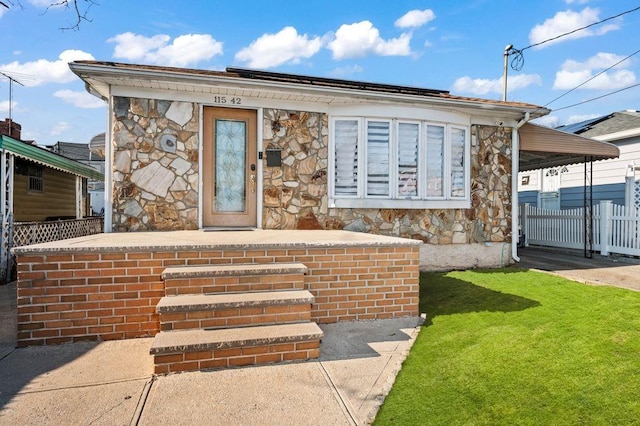 view of front of house featuring stone siding, fence, and a front lawn