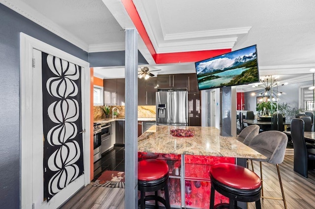 kitchen featuring crown molding, dark hardwood / wood-style floors, stainless steel appliances, and a kitchen breakfast bar