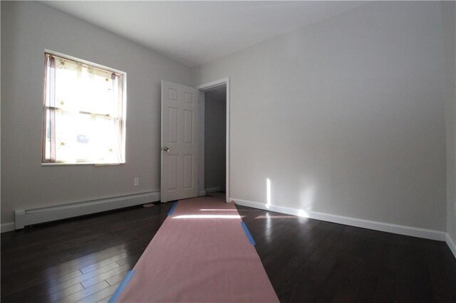 empty room with a baseboard radiator and dark hardwood / wood-style floors