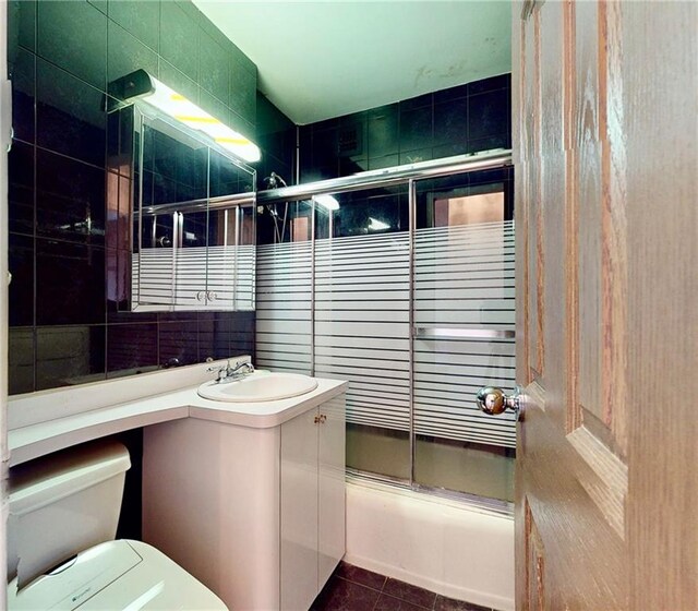 full bathroom featuring tile walls, shower / bath combination with glass door, vanity, toilet, and tile patterned floors