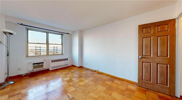 empty room featuring radiator, a wall mounted air conditioner, and light parquet floors