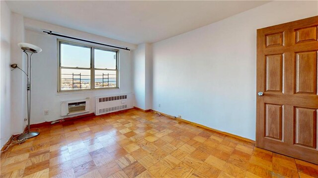 empty room featuring radiator, light parquet flooring, and a wall mounted AC