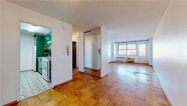 corridor featuring radiator, a sink, and baseboards