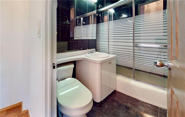 full bathroom featuring toilet, vanity, and bath / shower combo with glass door