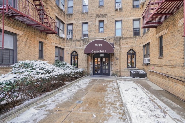 snow covered property entrance featuring cooling unit and french doors